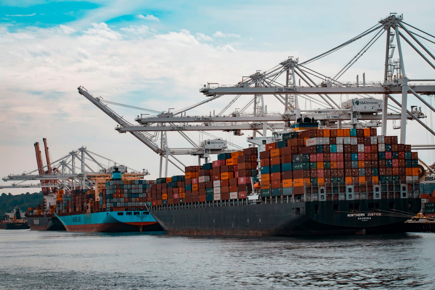 Shipping containers stacked at a port terminal under gantry cranes